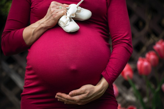 terhes nő babacipővel